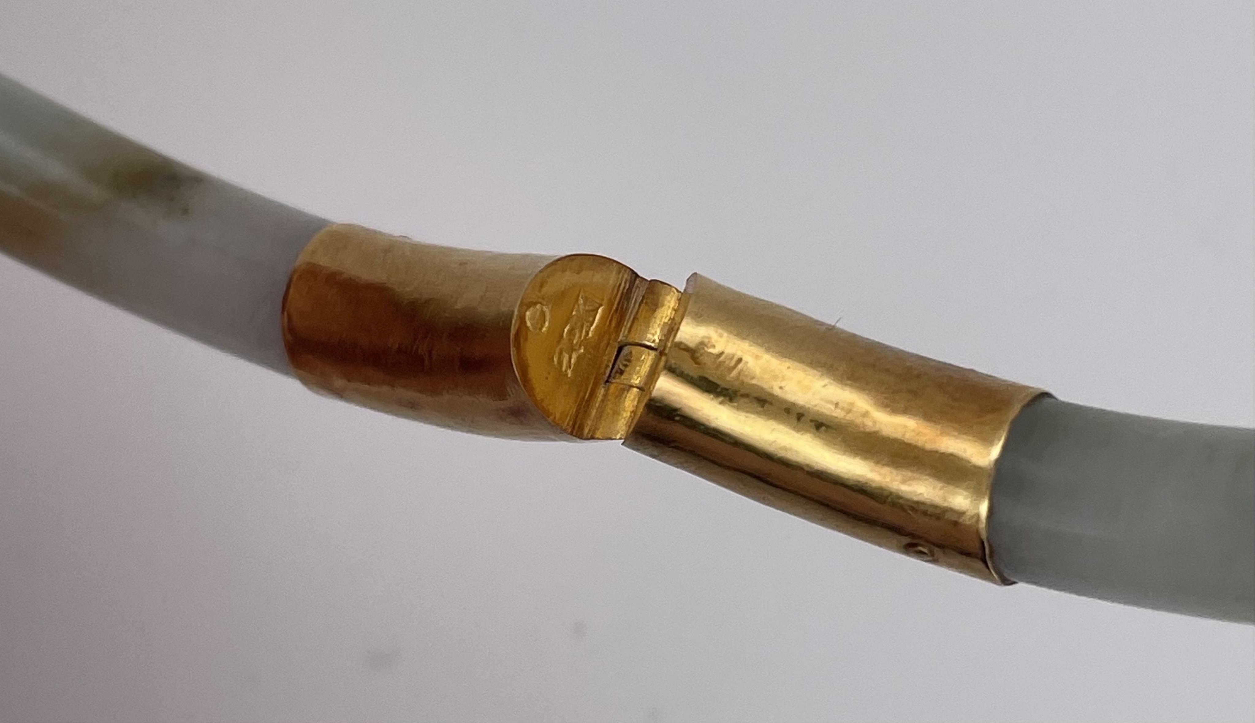 A jadeite and gold bangle, of hinged design, composed of a jadeite hoop mounted in gold, inner circumference approximately 15cm, stamped 22K